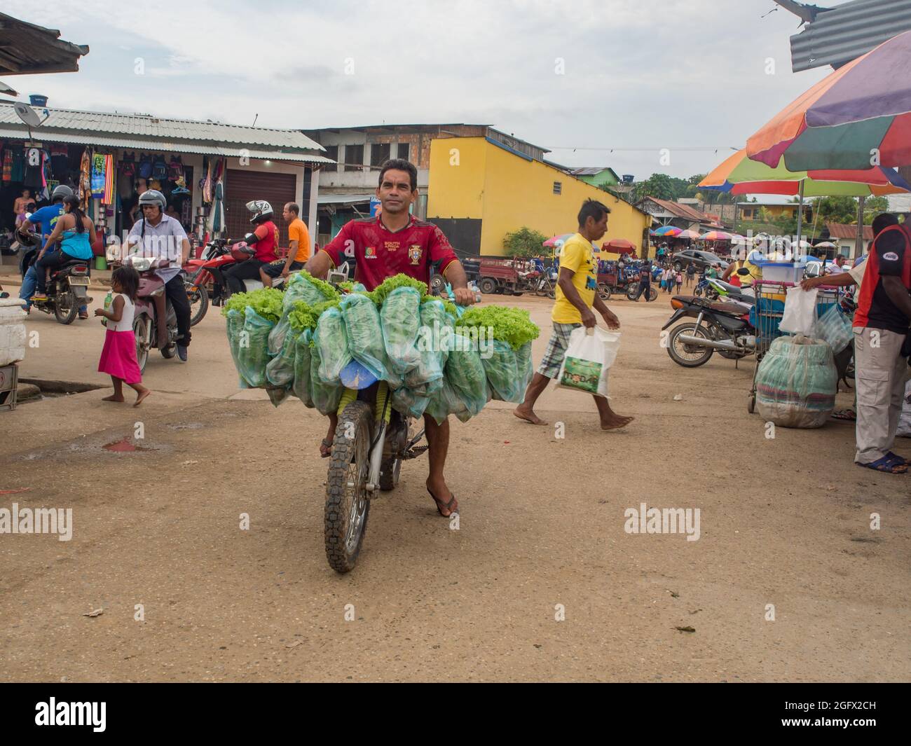 Tabatinga, Brazil - Sep 11, 2017: Peruvian man carrying the big numbers of green lettuce on the motor, bazaar near the port at Amazon river Stock Photo