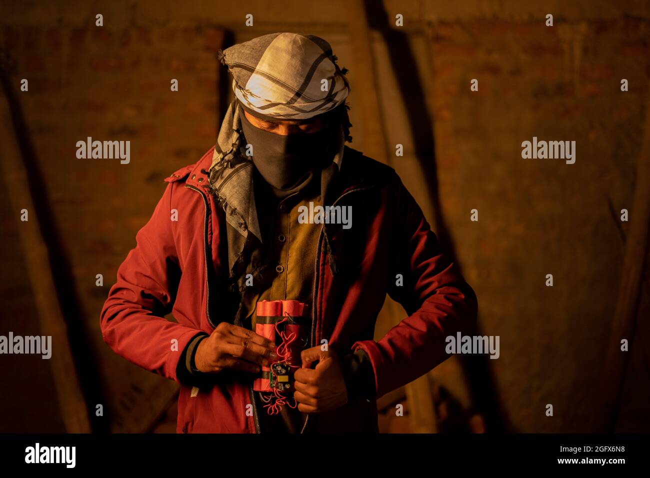concept of suicide bomber attack, Militant with face cover placing Dynamite inside the jacket Stock Photo
