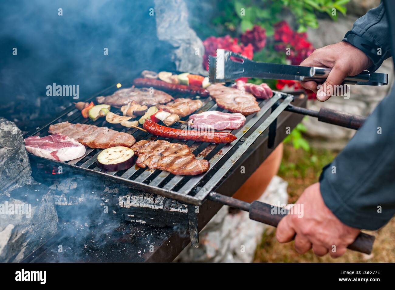Man cooking meat on barbecue grill at bbq party in summer garden. Food,  people and family time concept Stock Photo - Alamy