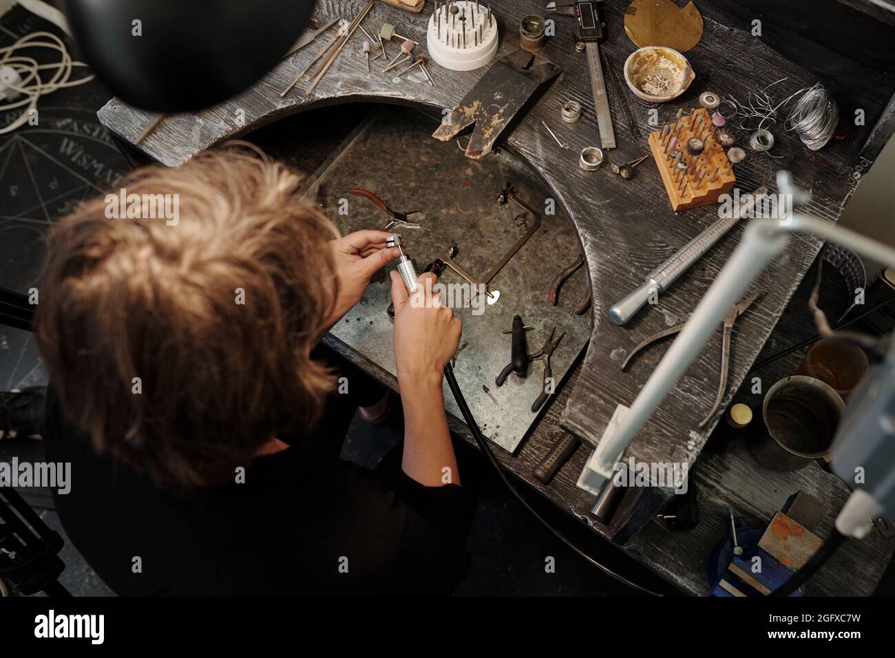 Directly above view of manufacturing jeweler using abrasive machine while making ring in jewelry workshop Stock Photo