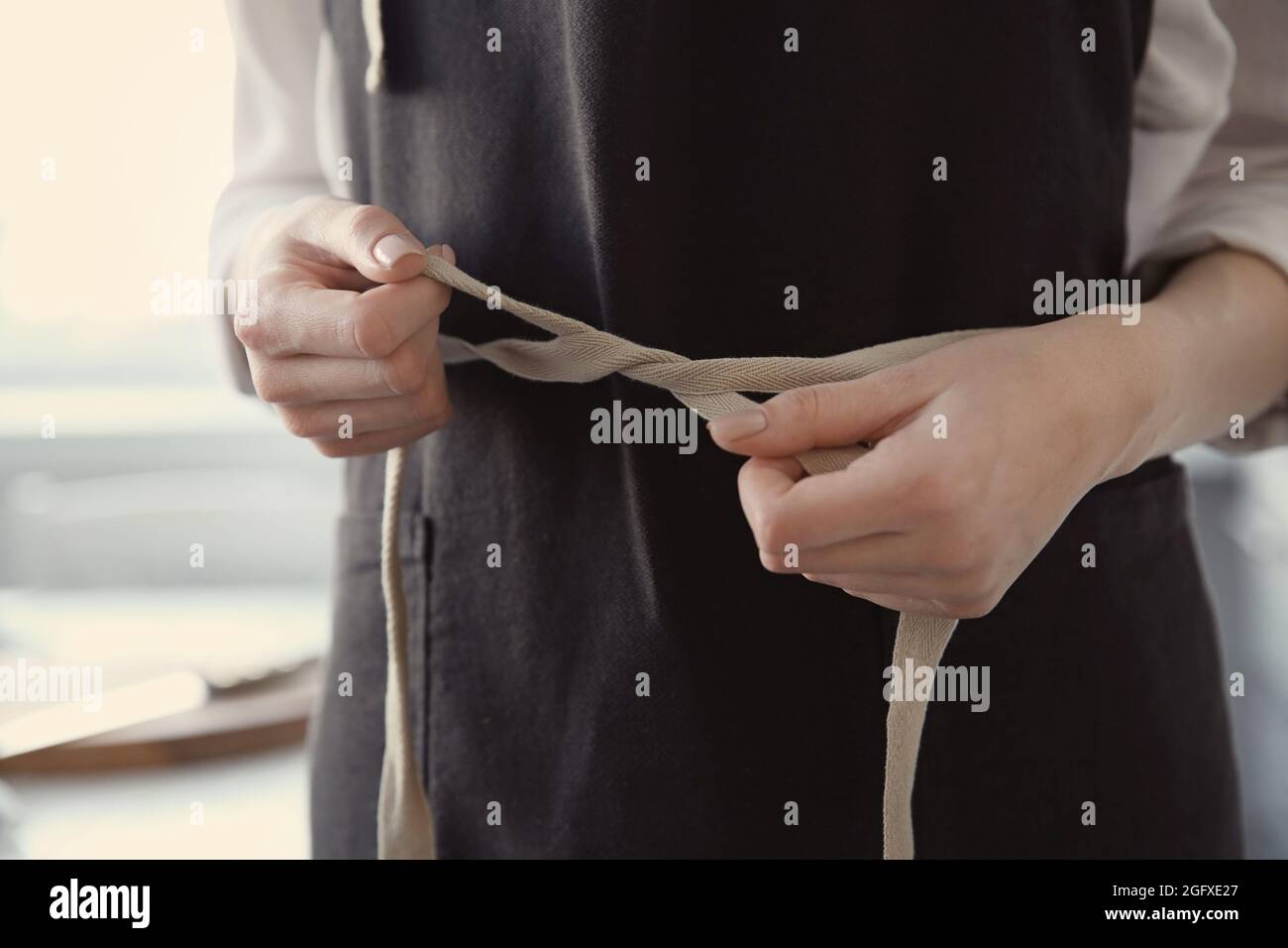 Woman tying up her apron around the waist Stock Photo Alamy