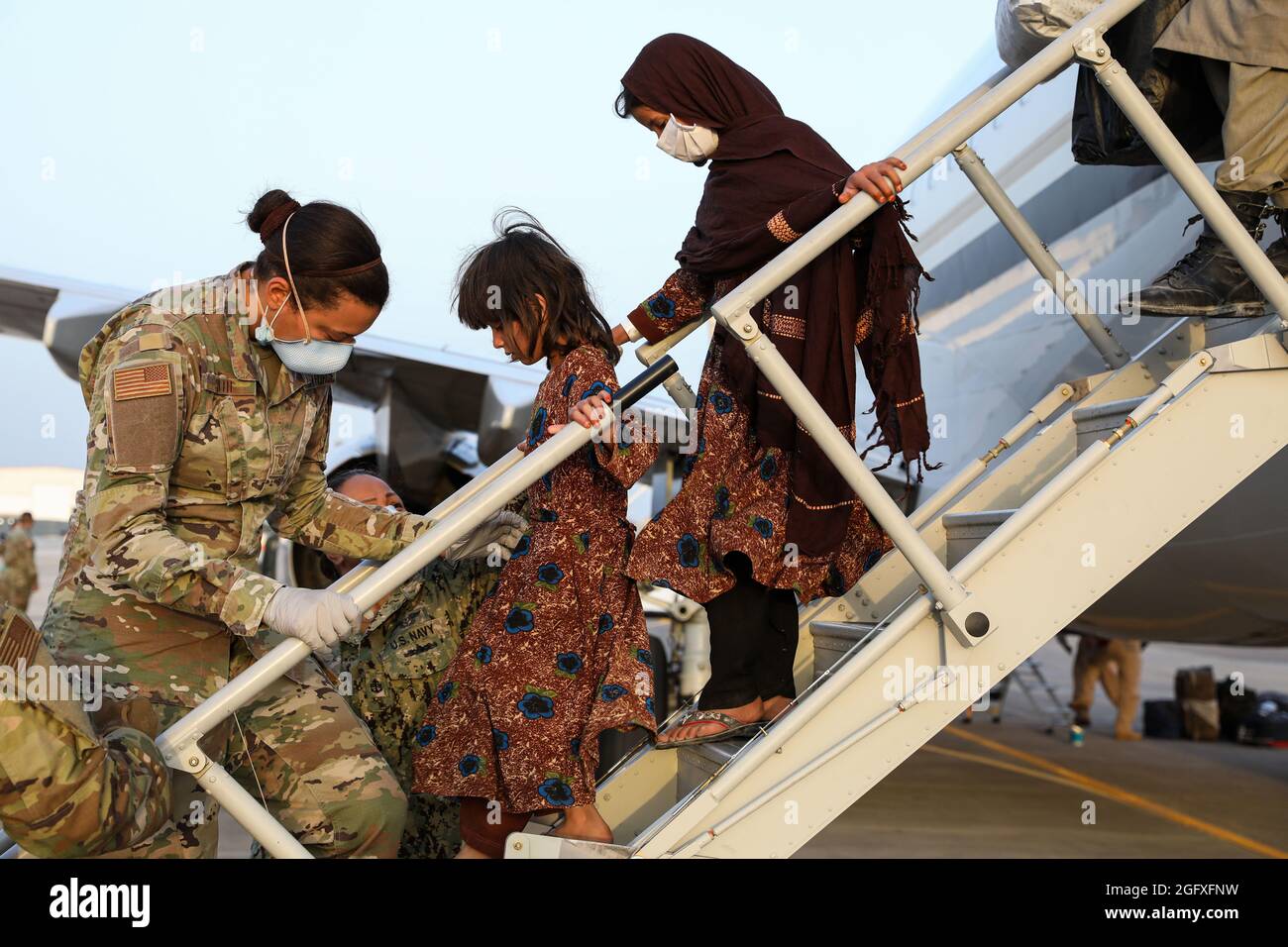 NAVAL AIR STATION SIGONELLA, Italy (Aug. 26, 2021) – U.S. Service members help Afghanistan evacuees depart a U.S. Air Force C-40B Clipper at Naval Air Station Sigonella Aug. 26, 2021. NAS Sigonella is currently supporting the Department of Defense mission to facilitate the safe departure and relocation of U.S. citizens, Special Immigration Visa recipients, and vulnerable Afghan populations from Afghanistan. NAS Sigonella’s strategic location enables U.S, allied, and partner nation forces to deploy and respond as required to ensure security and stability in Europe, Africa, and Central Command. Stock Photo