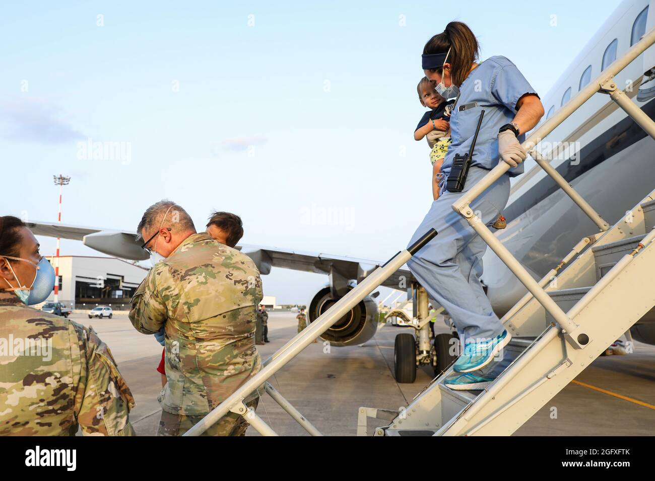 NAVAL AIR STATION SIGONELLA, Italy (Aug. 26, 2021) – U.S. Service members help Afghanistan evacuees depart a U.S. Air Force C-40B Clipper at Naval Air Station Sigonella Aug. 26, 2021. NAS Sigonella is currently supporting the Department of Defense mission to facilitate the safe departure and relocation of U.S. citizens, Special Immigration Visa recipients, and vulnerable Afghan populations from Afghanistan. NAS Sigonella’s strategic location enables U.S, allied, and partner nation forces to deploy and respond as required to ensure security and stability in Europe, Africa, and Central Command. Stock Photo