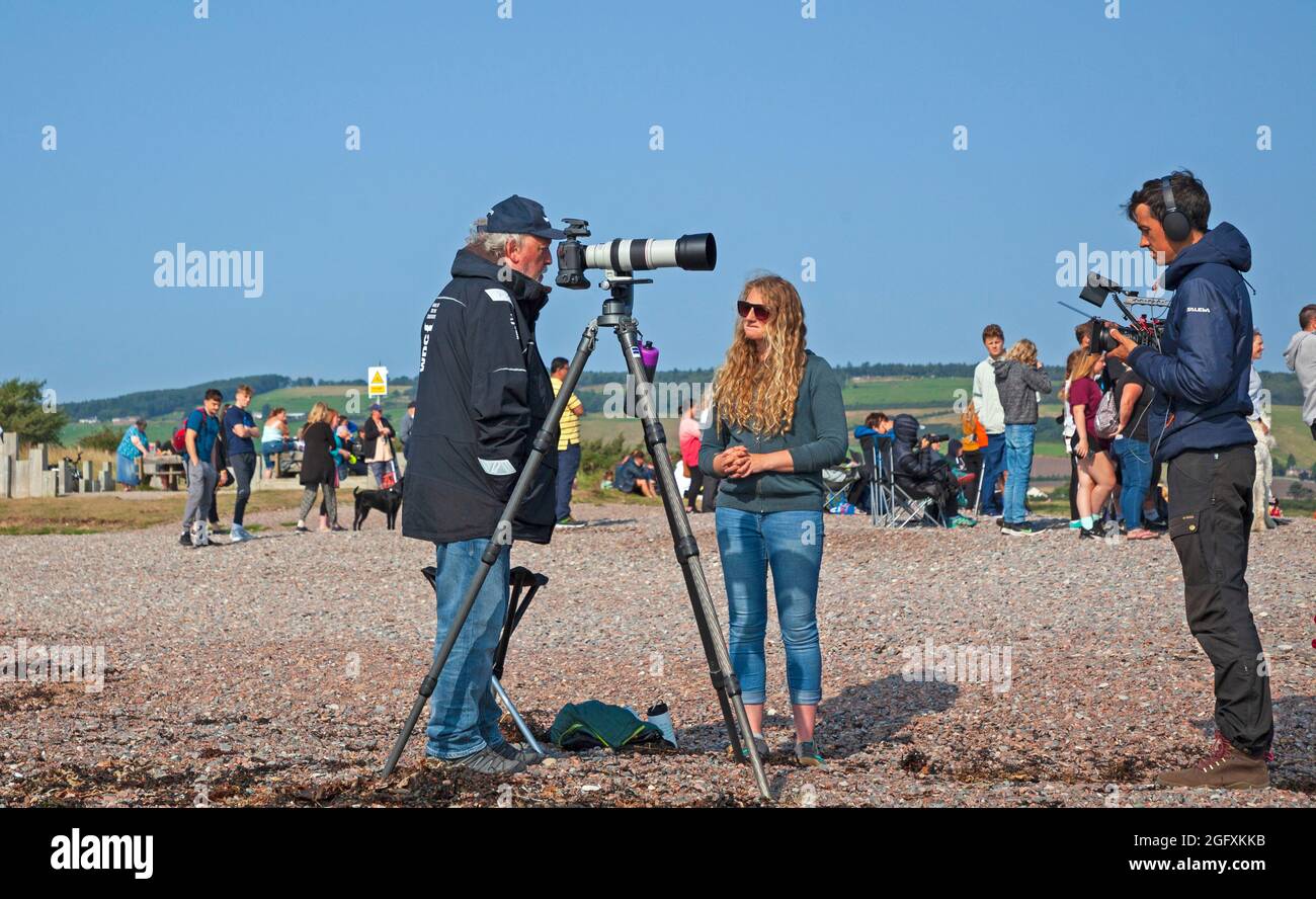 Fortrose Bay, Ross and Cromarty, Scotland, UK weather. 27th August 2021. Sunny after  a misty start for these potential Dolphin watchers, however unfortunately the Dolphins had a day off and did not arrive for the many photographers and tourists who turned up at the popular viewing areato see them. Pictured: Charlie Phillips Award winning pro wildlfe Photographer being interviewed for an independent film Credit: Arch White/Alamy Live News Stock Photo