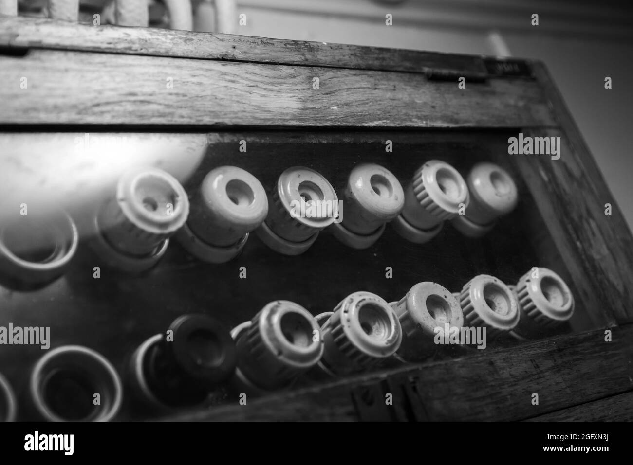 Vintage electrical fuses mounted on a  dark panel in wooden case,  black and white photo Stock Photo