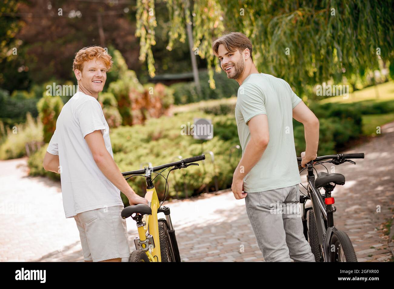 Two sporty young people with bicycles looking at something Stock Photo