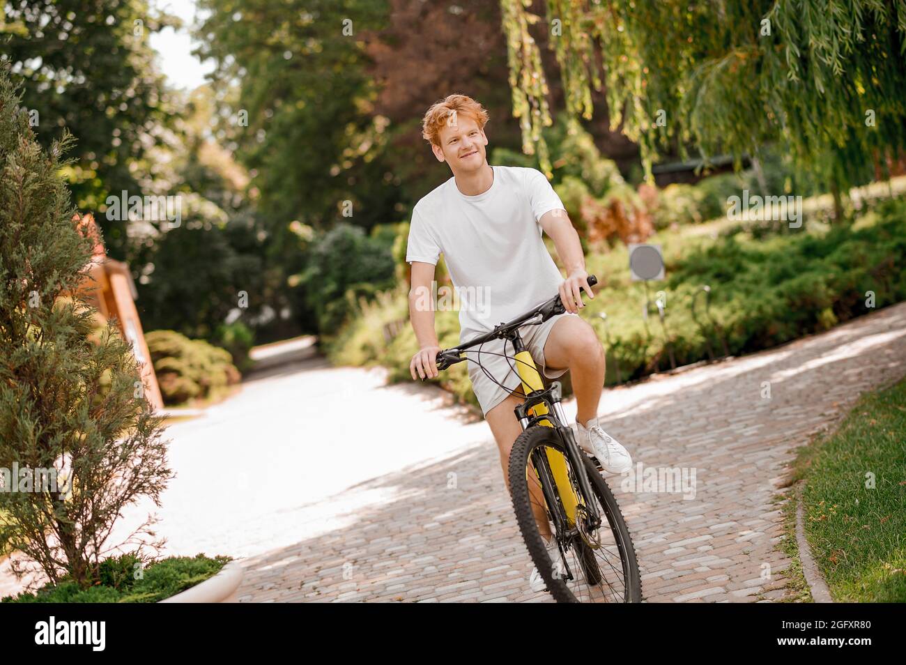 Contented young bike rider cycling alone outdoors Stock Photo