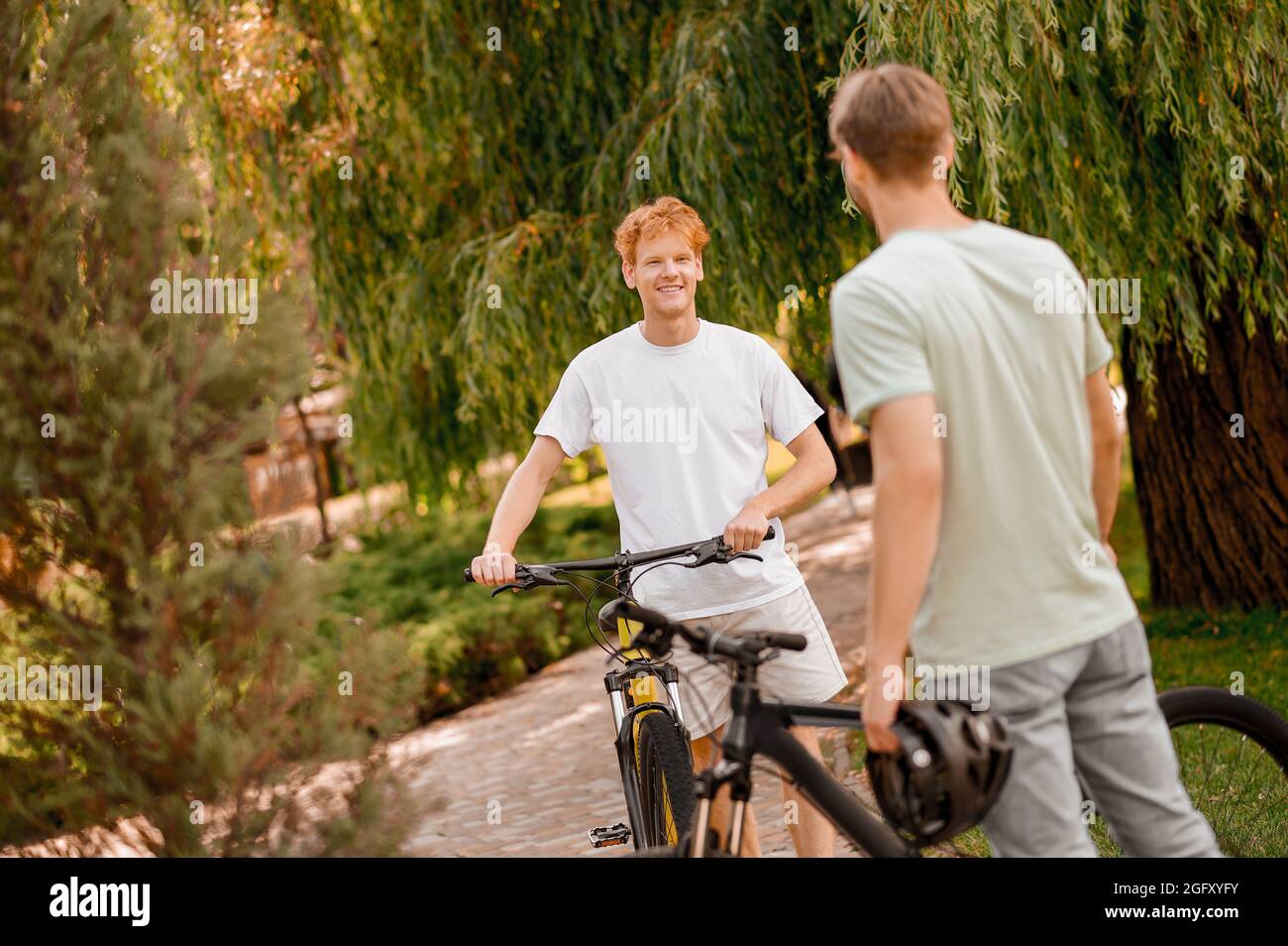Joyous young bicyclist chatting with his frien Stock Photo