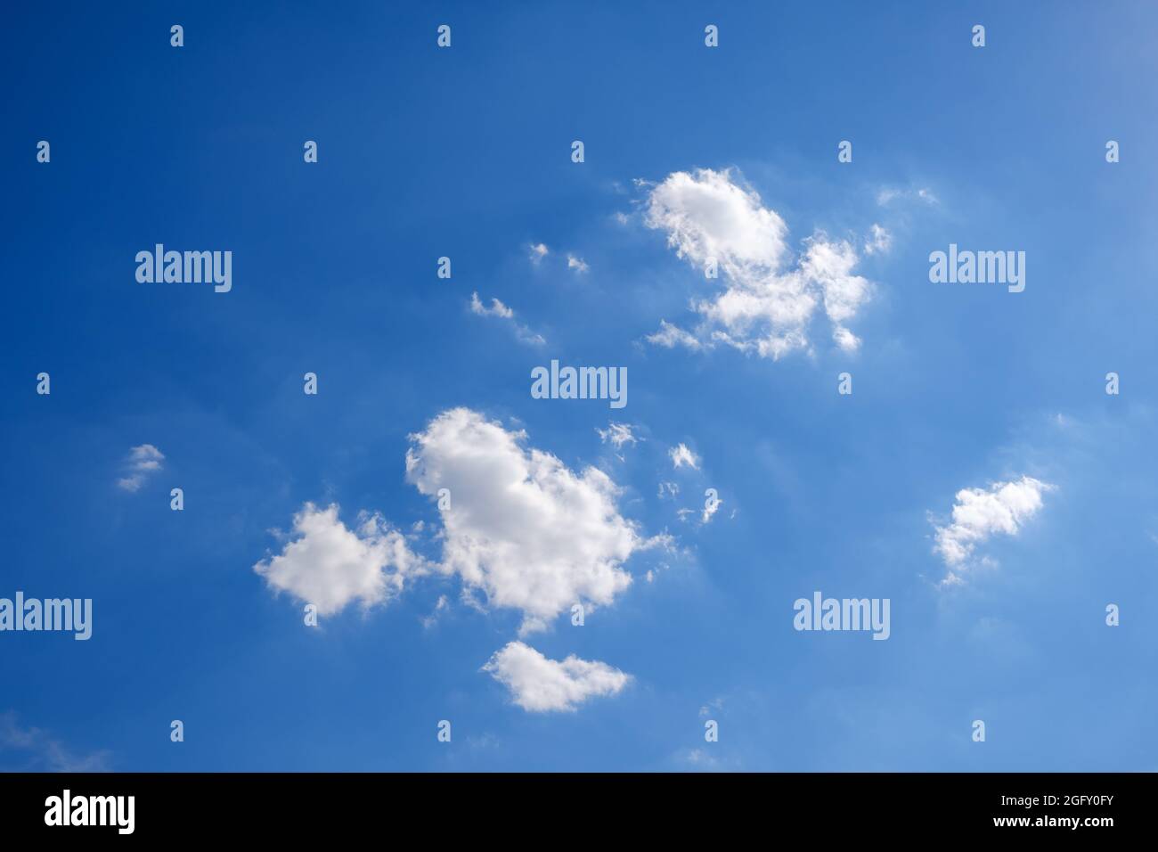 Some fluffy white clouds on a deep blue sky in summer Stock Photo