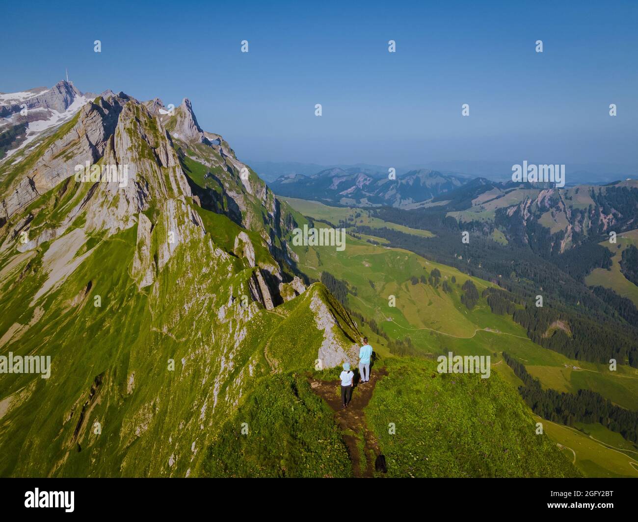 A woman with a backpack stands on top of a mountain, The girl travels to beautiful places, Reaching the goal, mountain ridge at Saxer Lucke, Kreuzberg in Alpstein Appenzell Innerrhoden Switzerland.  Stock Photo