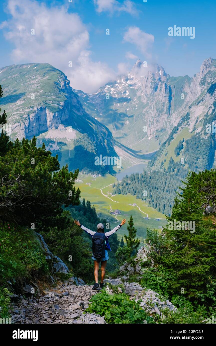 A woman with a backpack stands on top of a mountain, The girl travels to beautiful places, Reaching the goal, mountain ridge at Saxer Lucke, Kreuzberg in Alpstein Appenzell Innerrhoden Switzerland.  Stock Photo