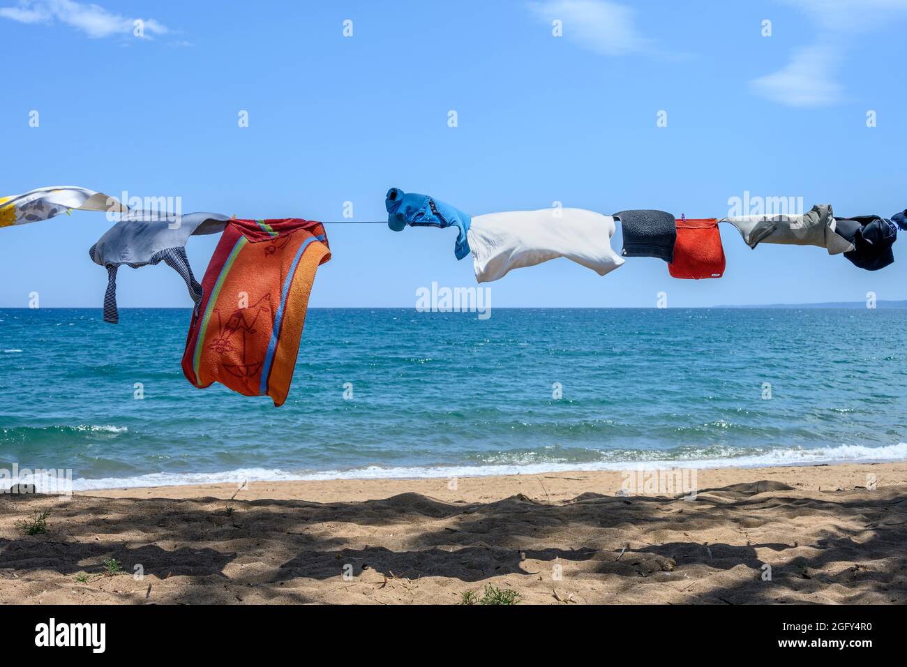 Campers clothes on a washing line next to the sea on a beach in Southern Greece. Stock Photo