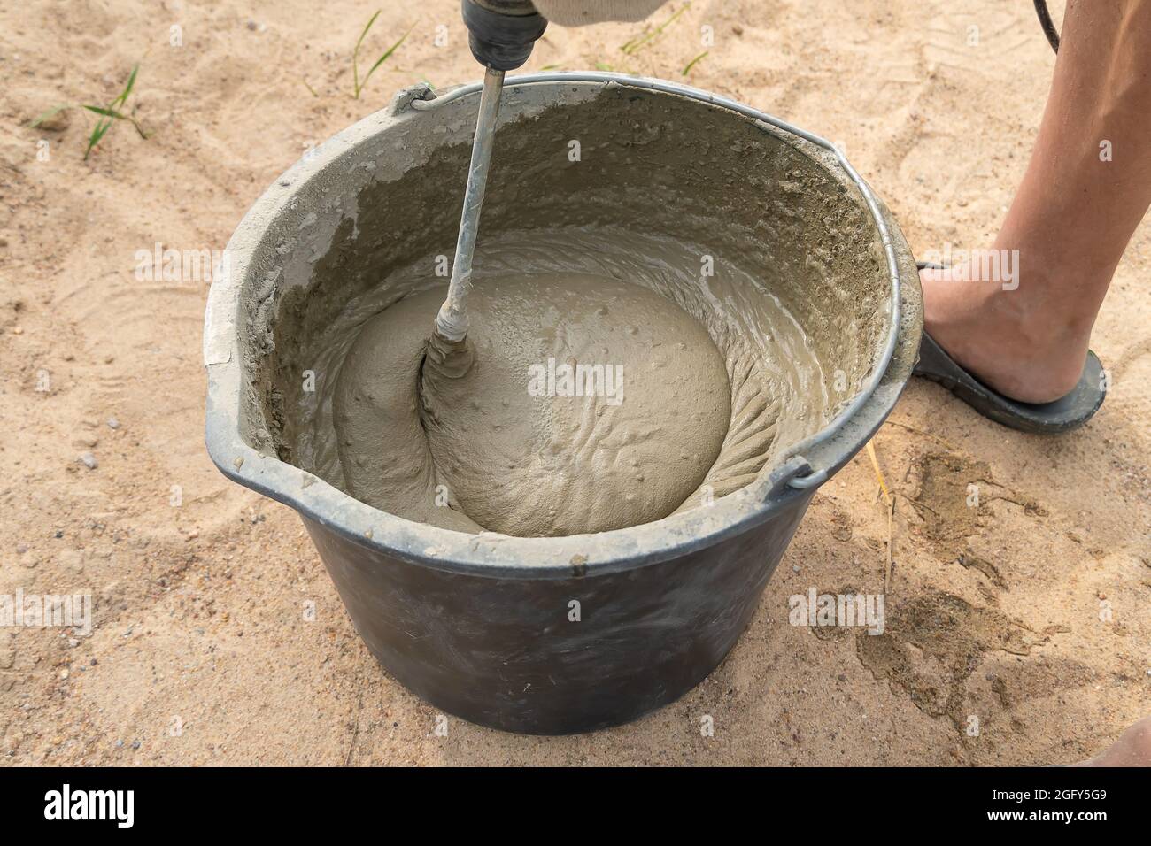 Mixing cement mortar in a bucket with an electric construction drill