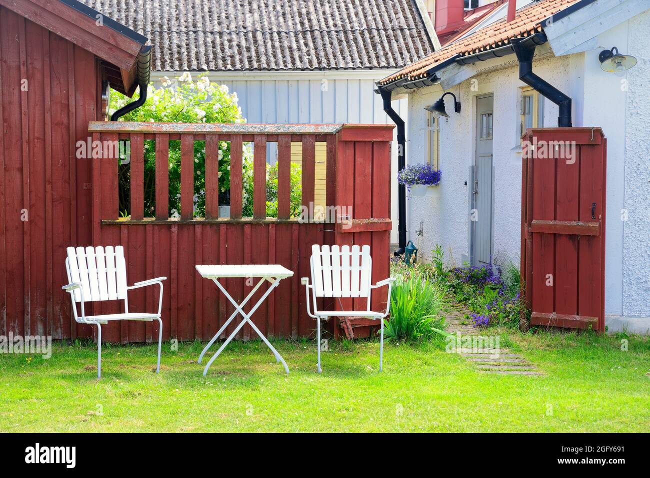 Traditional white garden furniture in front of old red hous Stock Photo