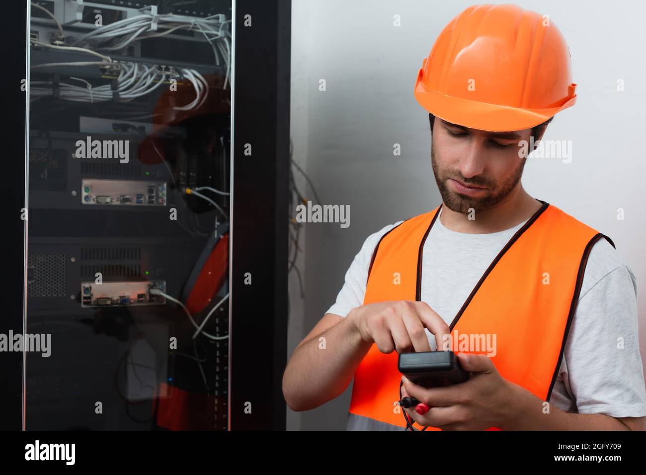 Workman in helmet holding electrical tester near switchboard Stock Photo Alamy