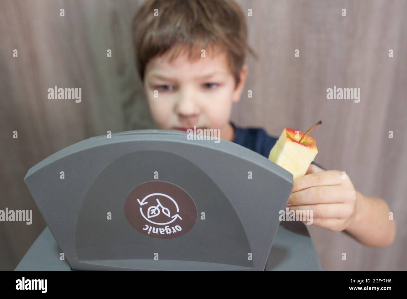 Child boy throwing apple core to waste bin for organic at home. Education about Waste Segregation concept Stock Photo