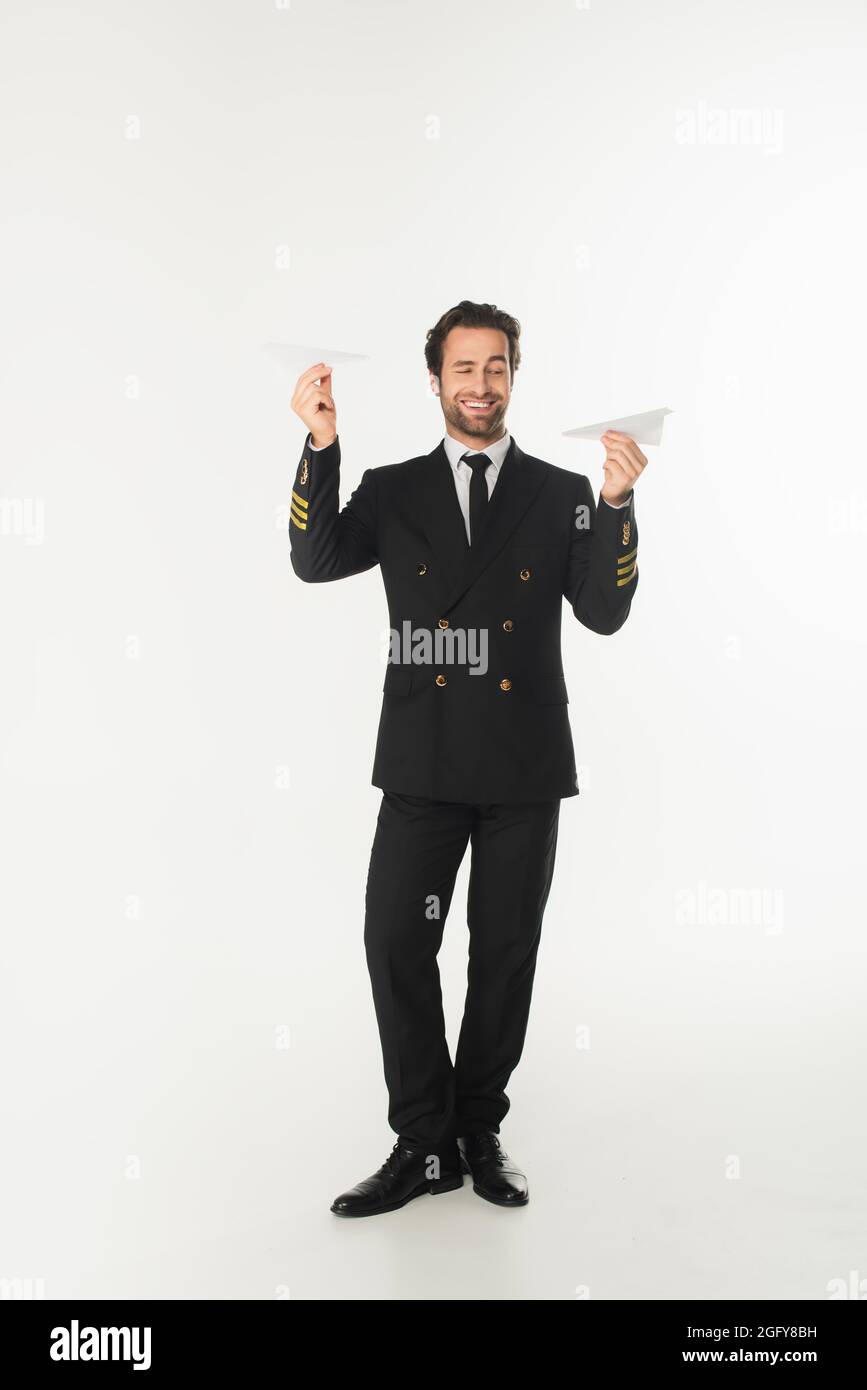 Smiling pilot holding paper planes on white background Stock Photo