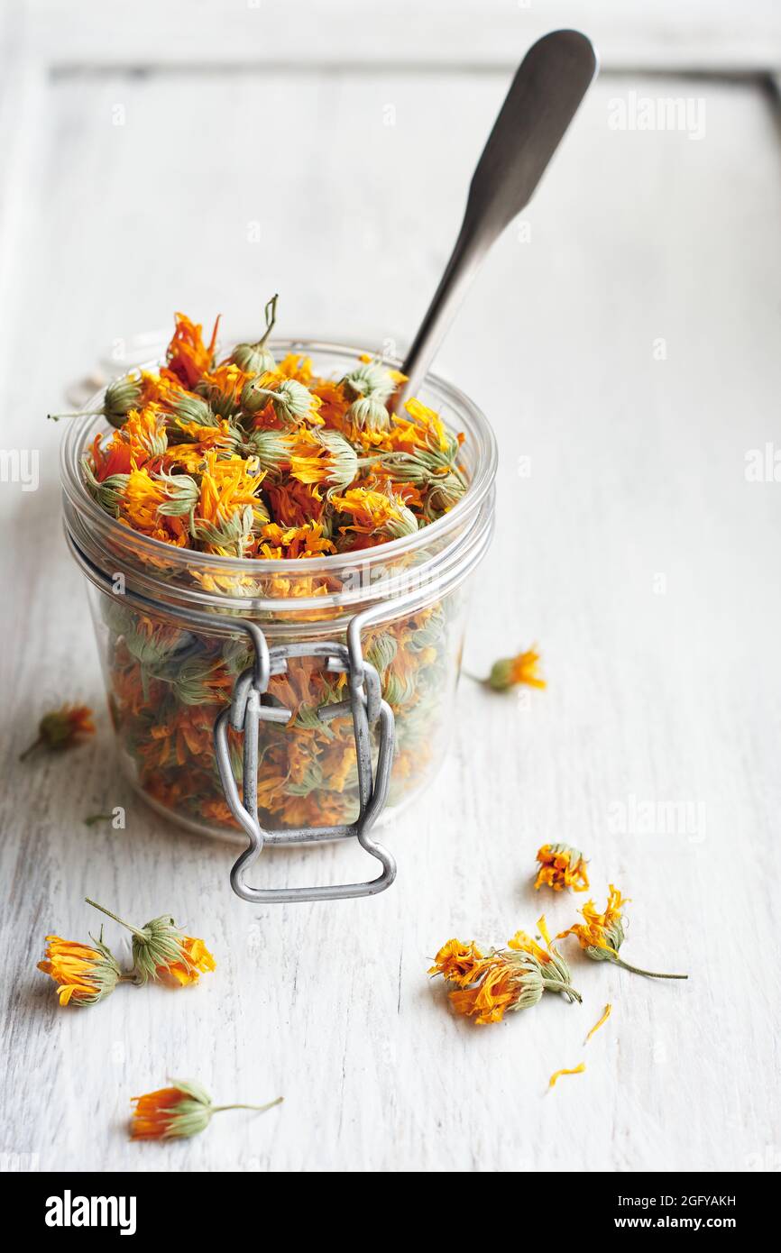 Dried marigold flowers in a jar on white wood Stock Photo Alamy