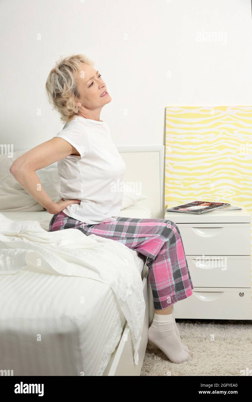 Senior woman suffering from backache while sitting on bed at home Stock Photo Alamy