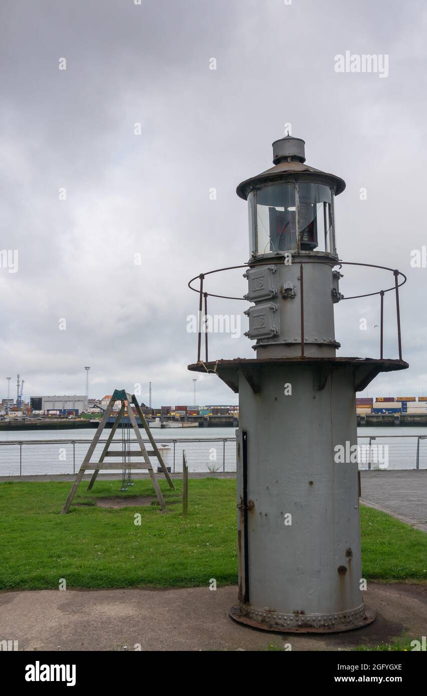 Zeebrugge Port, Belgium - August 6, 2021: Historic gray metal light signal tower on display along Paardenmarktstraat with container terminal in back u Stock Photo