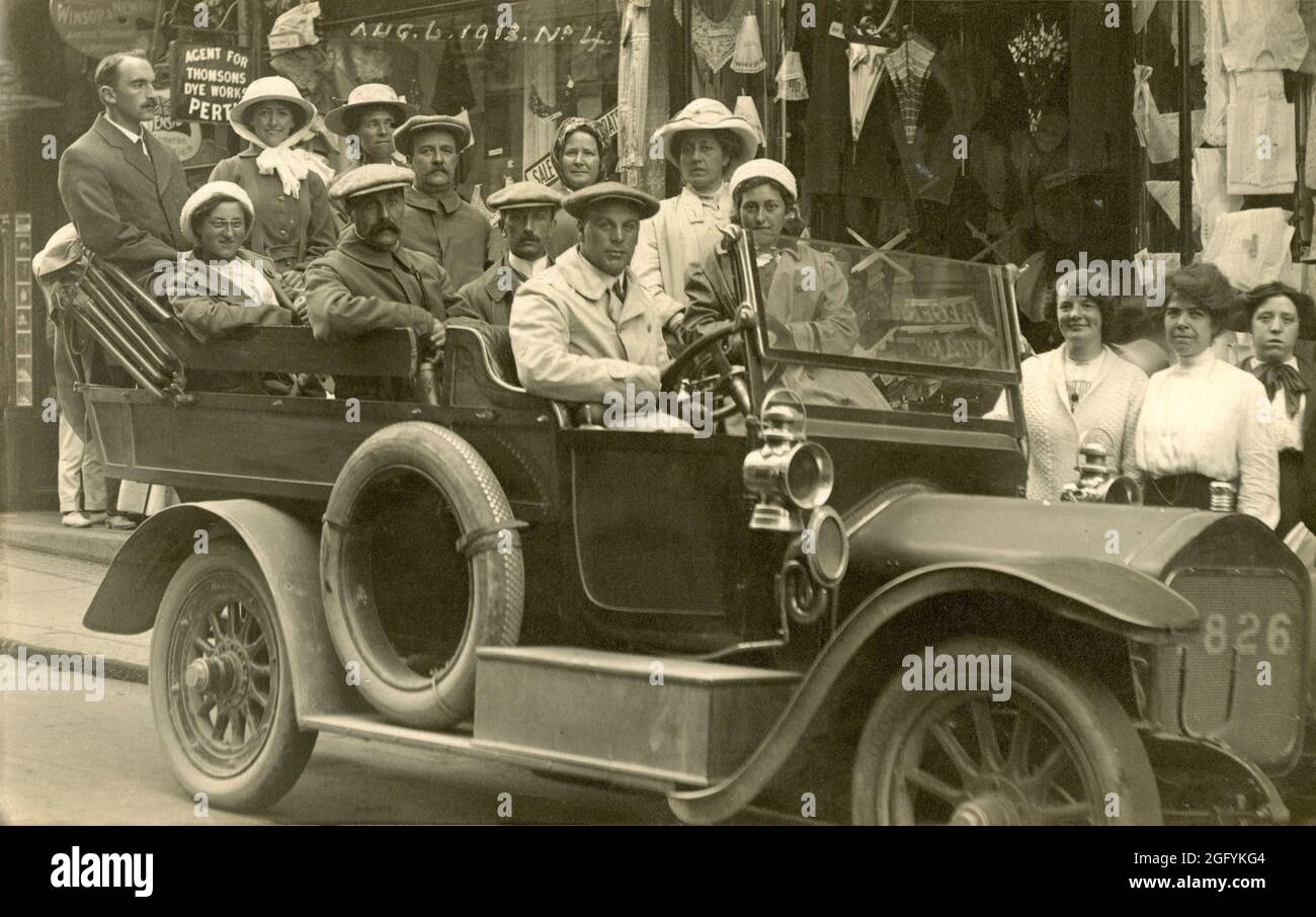 1913, a historical picture showing a group of people sitting in a motor vehicle, a Charabanc, in a street at at lIfracomble, Devon, England, UK before a sight-seeing trip  Originating in France in the 19th Century, and taken from the French word 'char a bancs' - literally, a wagon with benches - a Charabanc was an open-topped motor coach with rows of forward-facing seats. They were popular motor vehicles in Britain in the early part of the 20th century for providing large groups with day trips, excusions and works outings. Stock Photo