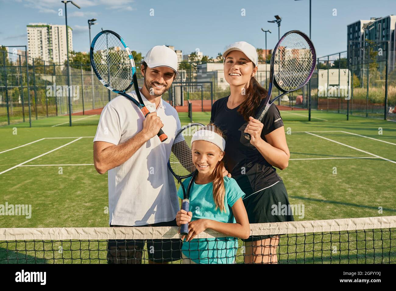 Sporty family playing tennis. Happy tennis family posing on green tennis  court outdoor with rackets Stock Photo - Alamy