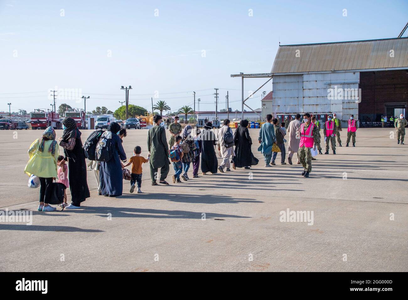 Rota, Spain. 27th Aug, 2021. U.S. Navy sailors assist Afghan refugees evacuated from Kabul on arrival at Naval Station Rota August 27, 2021 in Rota, Spain. NS Rota is providing temporary lodging for evacuees from Afghanistan as part of Operation Allies Refuge. Credit: Planetpix/Alamy Live News Stock Photo