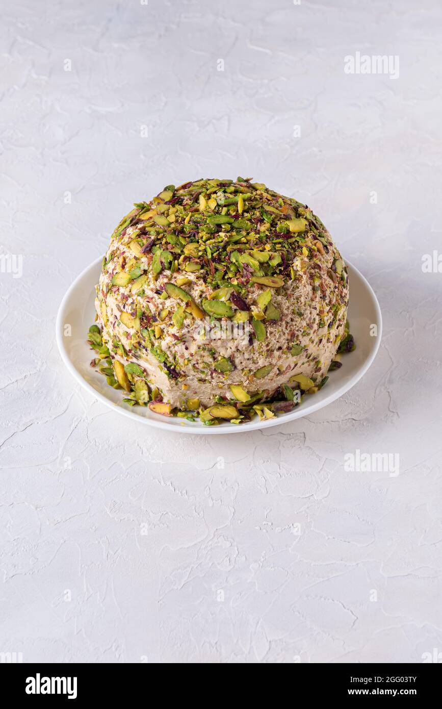 Sesame halva with pistachios nuts on white plate on white background. High angle view. Copy space. Traditional middle eastern sweets. Jewish, turkish, Stock Photo