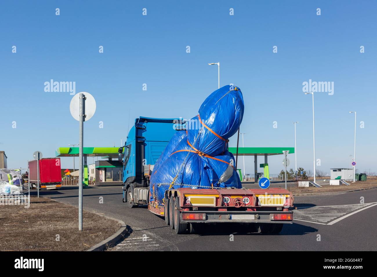 Blue truck with special semi-trailer for oversized loads transportation. Oversize load on flatbed trailer. Stock Photo