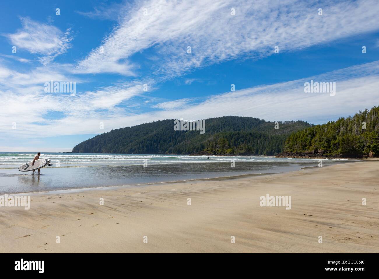 Man with SUP coming out of water at San Josef Bay, Cape Scott Provincial Park, Vancouver Island