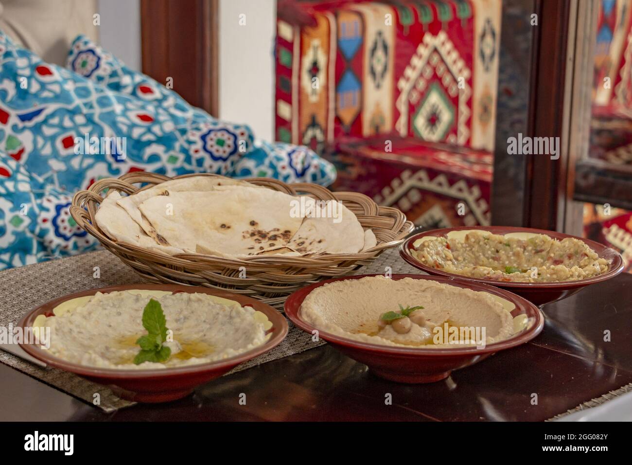 Closeup of bowls of hummus, mutabal and pita bread served at a Middle Eastern cuisine restaurant Stock Photo