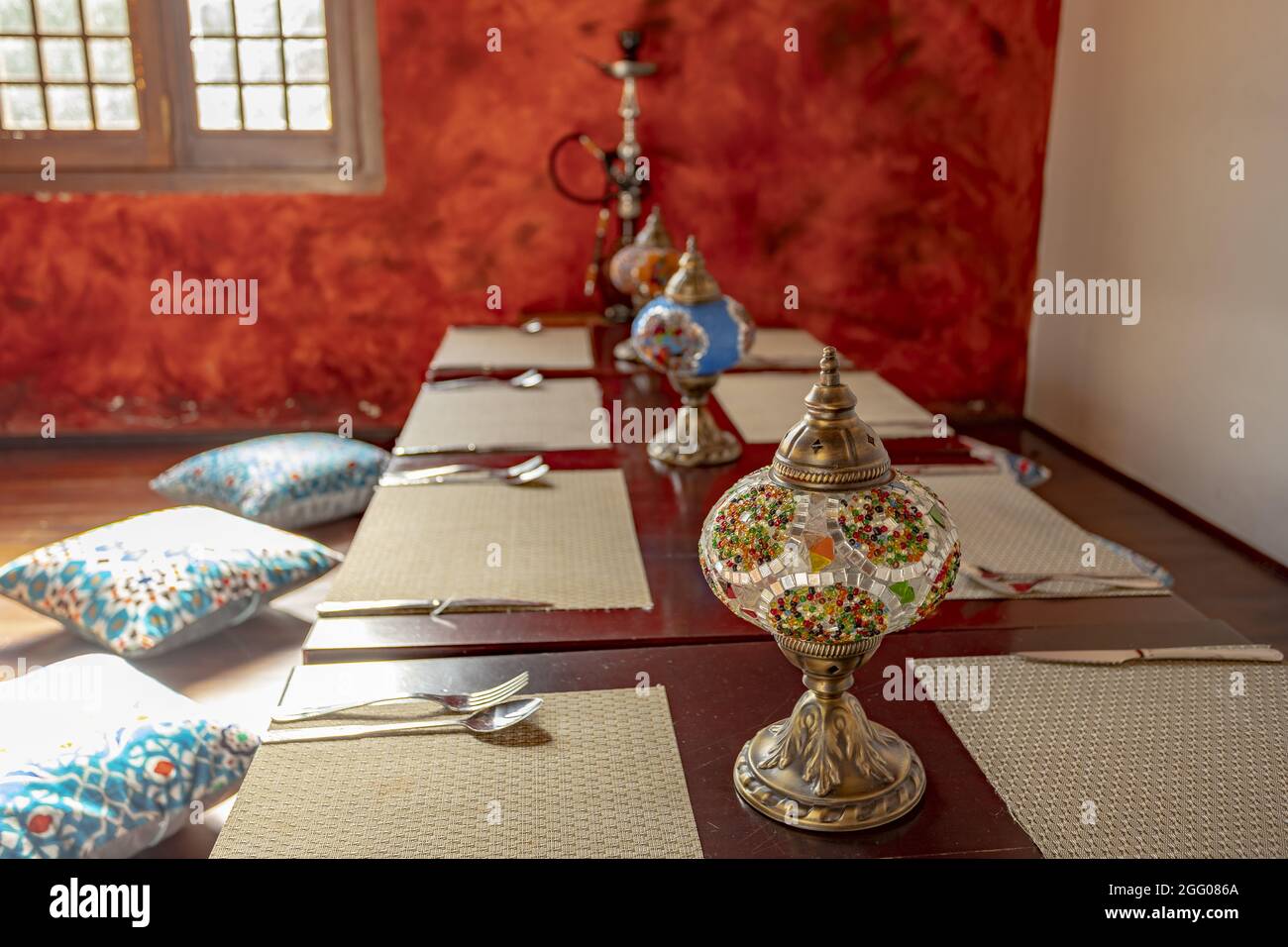 Traditional Middle Eastern dining setting with woven mats on tables and pillows on the floor Stock Photo