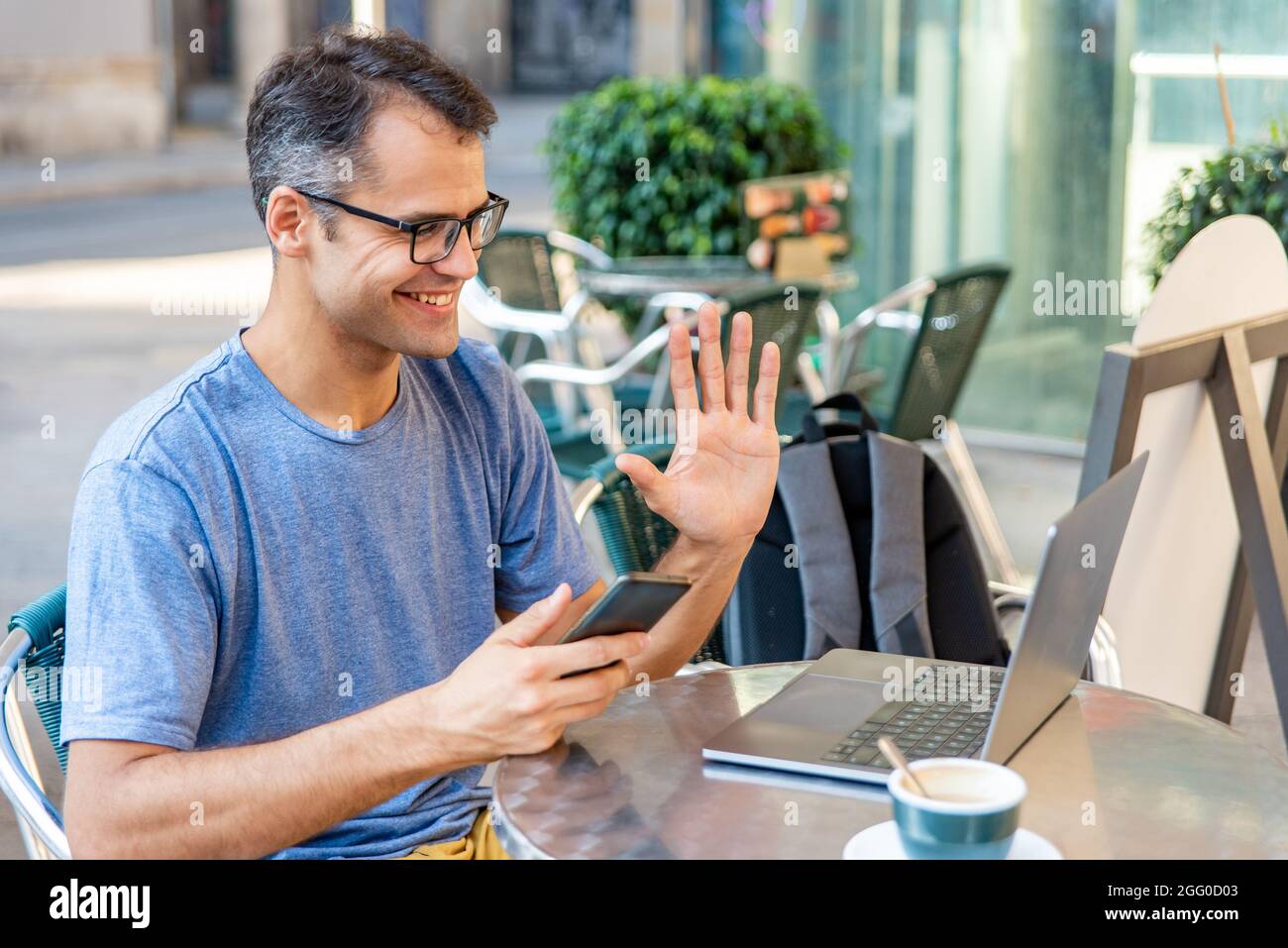 Young latin man video calling with computer outside. Stock Photo