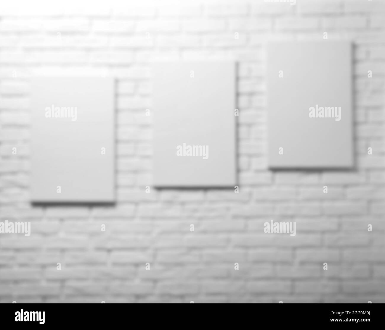 Blurred view of empty canvases on white brick wall background Stock