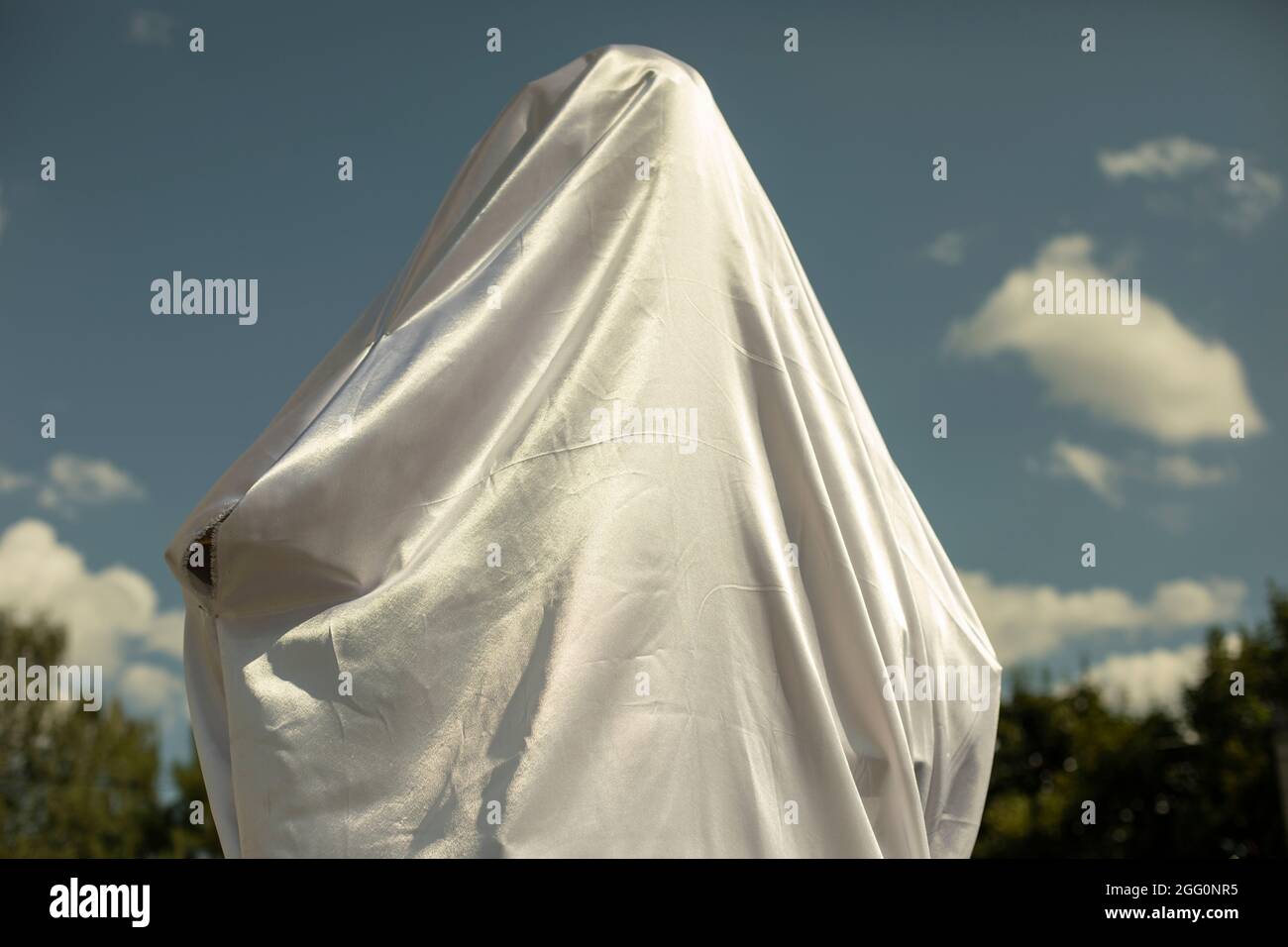 White fabric covers the figure. Opening of the cultural monument. Solemn white fabric on the monument. Stock Photo