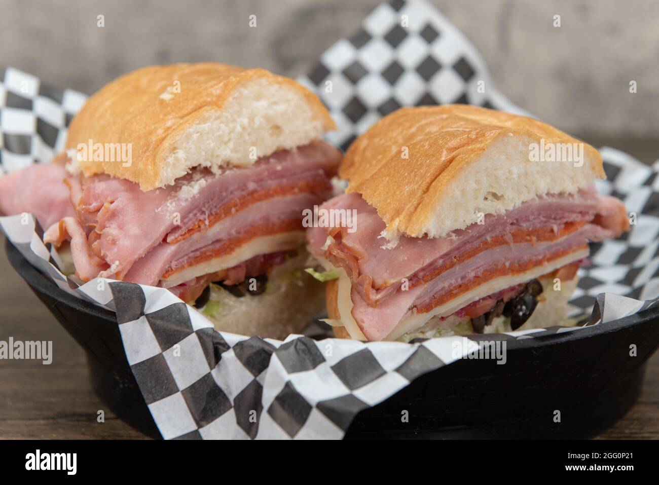 Ham, salami, pepperoni, and provolone cheese are layed and stack tall in this sandwich for an appetizing meal. Stock Photo