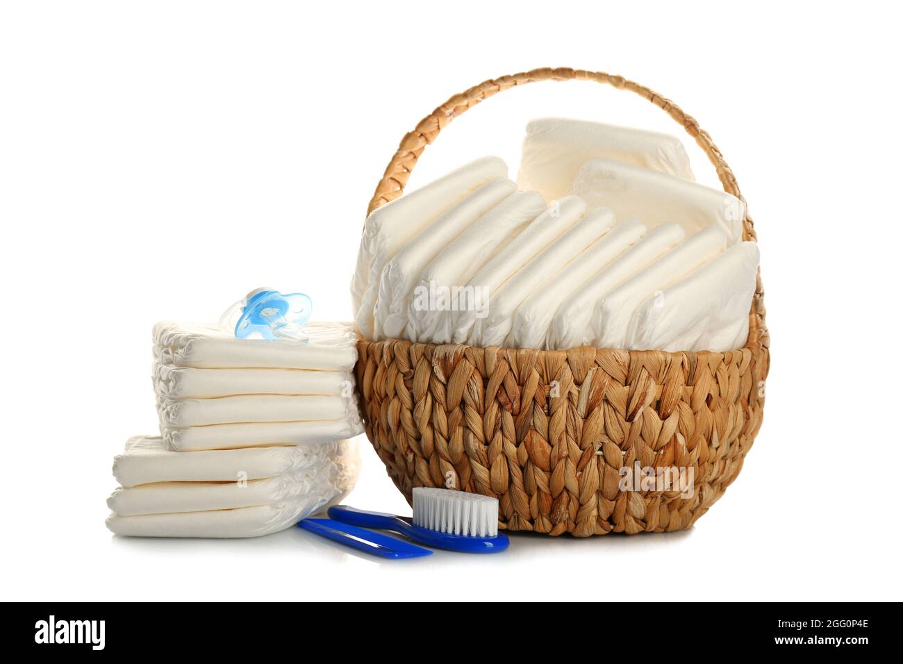 Baby diapers in wicker basket and necessities on white background Stock