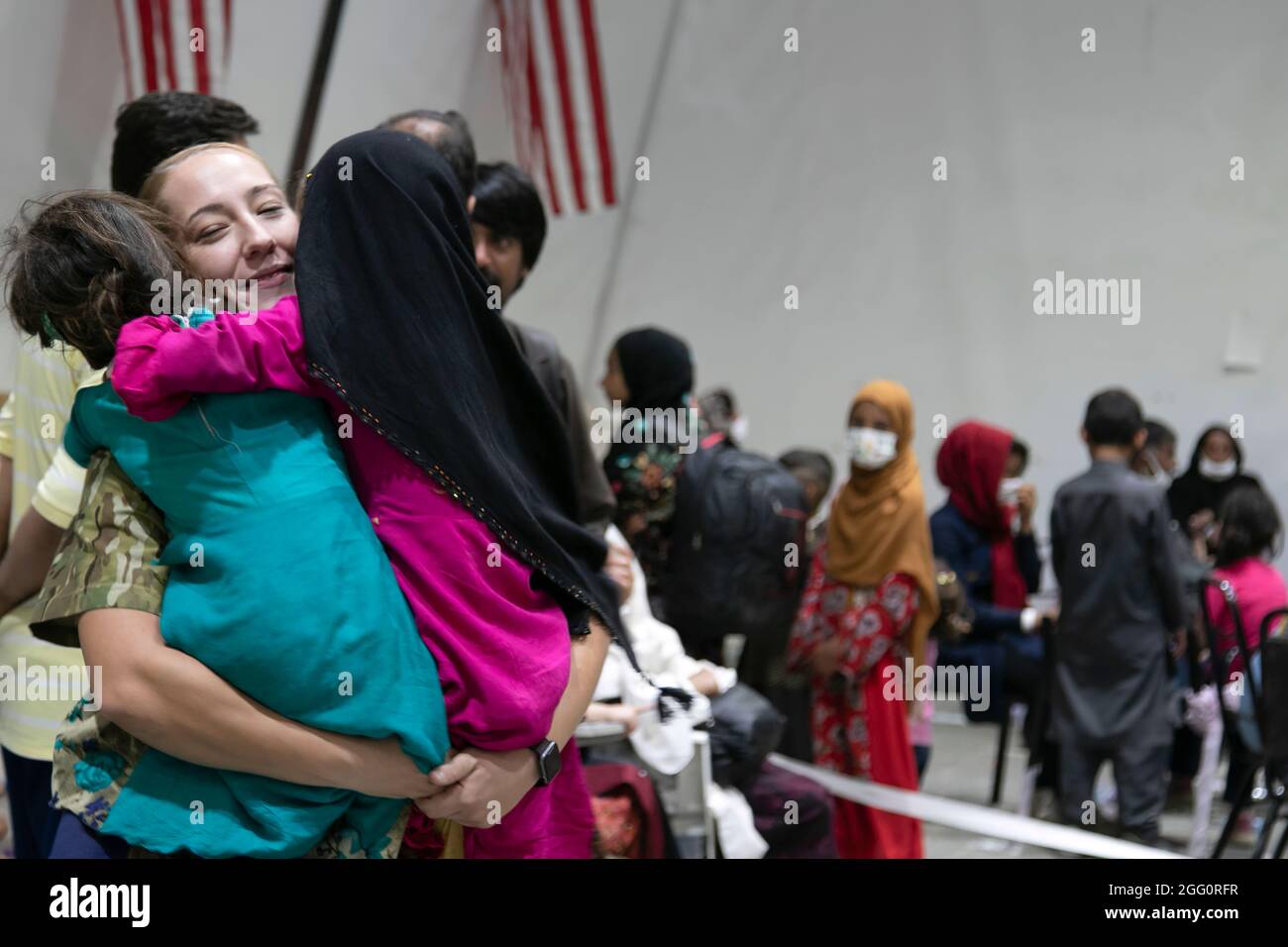 A U.S. Army Central Soldier welcomes Afghan evacuee girls with hugs during the arrival processes at Camp Buehring, Kuwait, Aug. 25, 2021. USARCENT Soldiers hit it off quickly with the children at the facility, finding ways to bring smiles and laughs through the process. (U.S. Army photo by Sgt. Marc Loi) Stock Photo