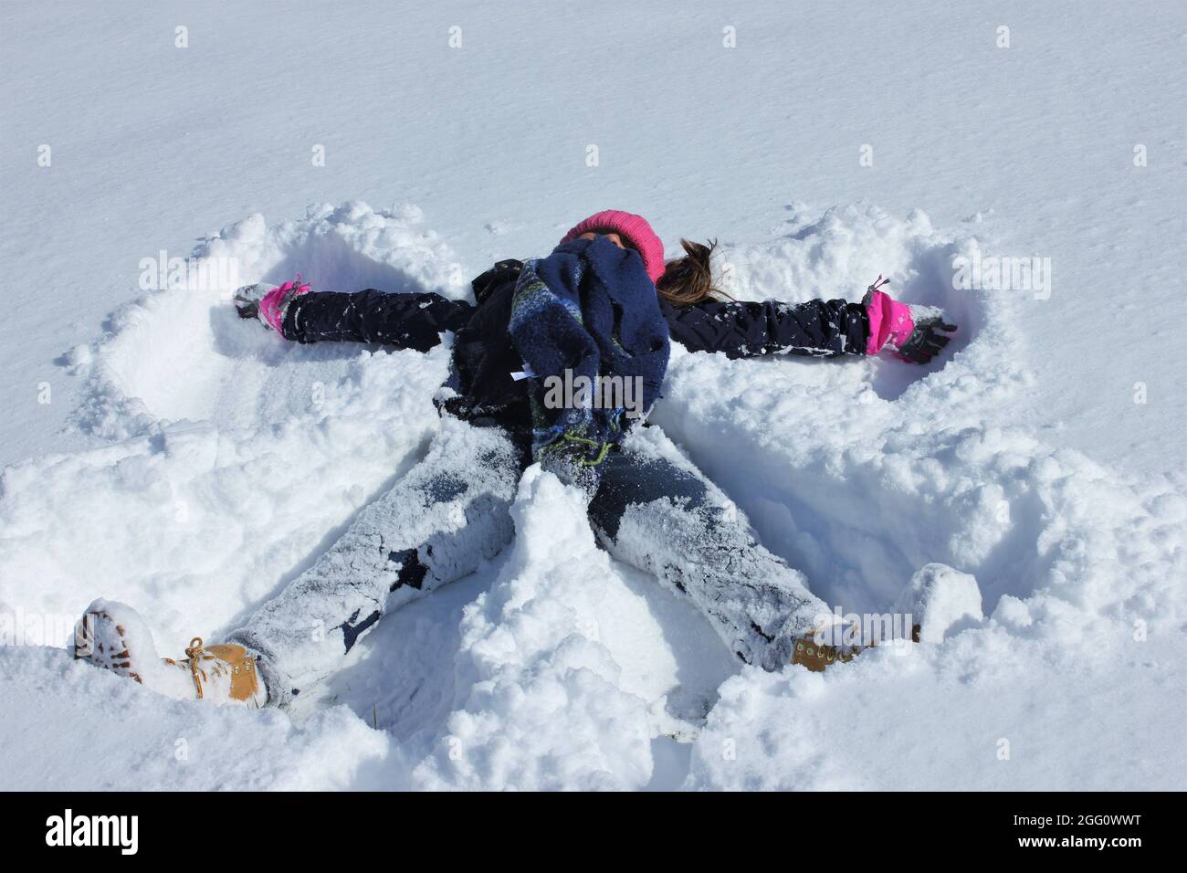 A young girl having fun in the winter making a snow angel Stock Photo