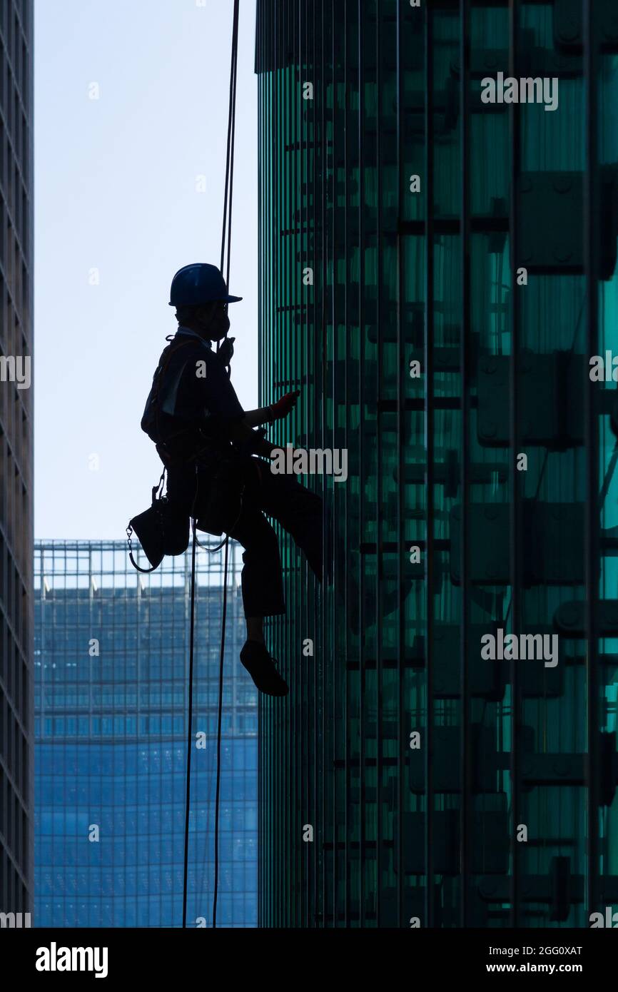 A window cleaner using abseil ropes to clean the windows of an glass