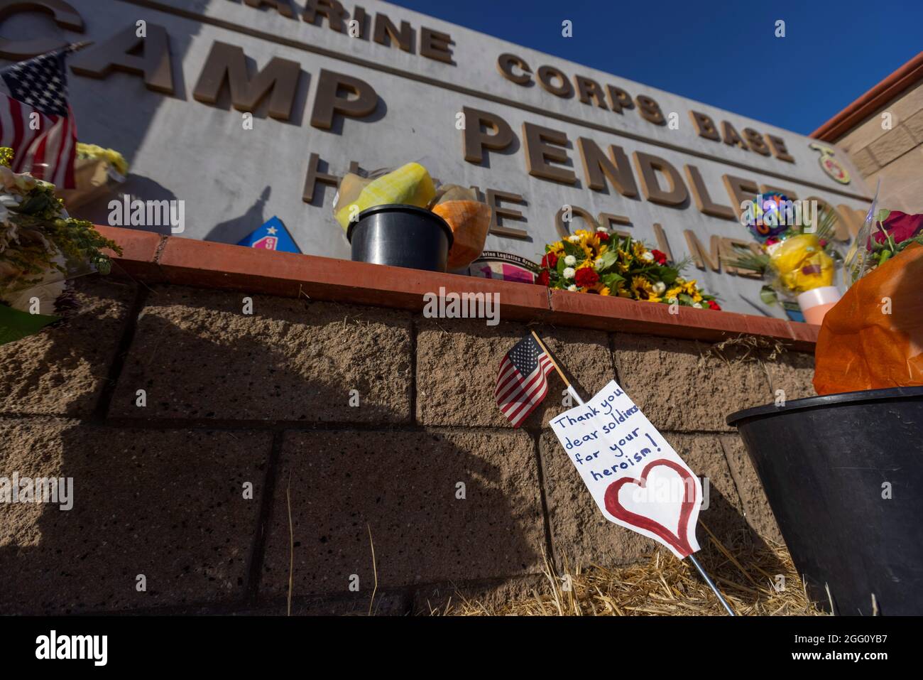 Following the bombing at Hamid Karzai International Airport in Kabul, Afghanistan, flowers and other tributes are shown placed at the main gate to U.S. Marine Base Camp Pendleton in Oceanside, California, U.S., August 27, 2021.      REUTERS/Mike Blake Stock Photo