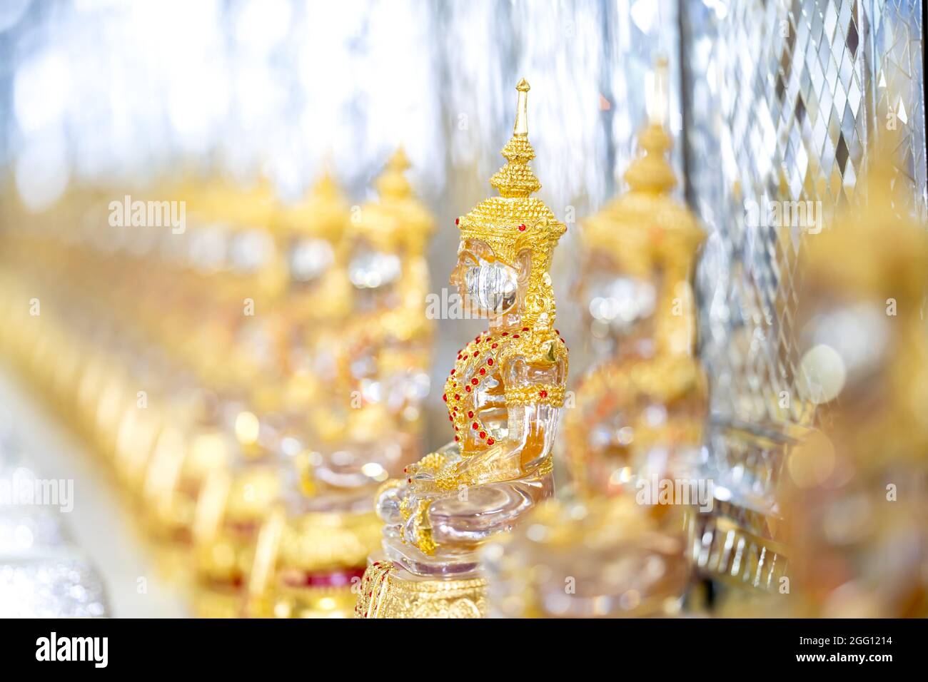 Transparent crystal Buddha in Gold suit with blur bokeh shining background. Stock Photo