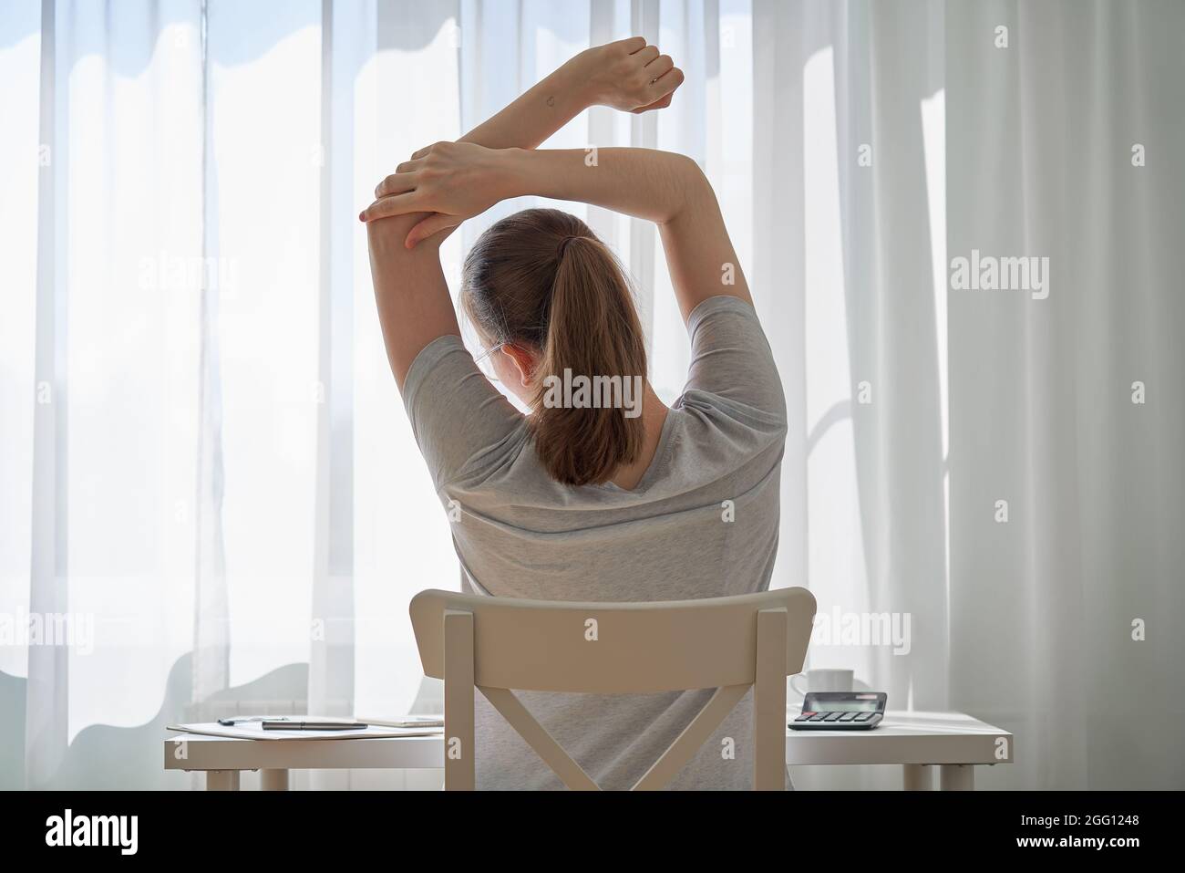 Faceless young female working from home and feeling discomfort in back. Remote work challenges Stock Photo
