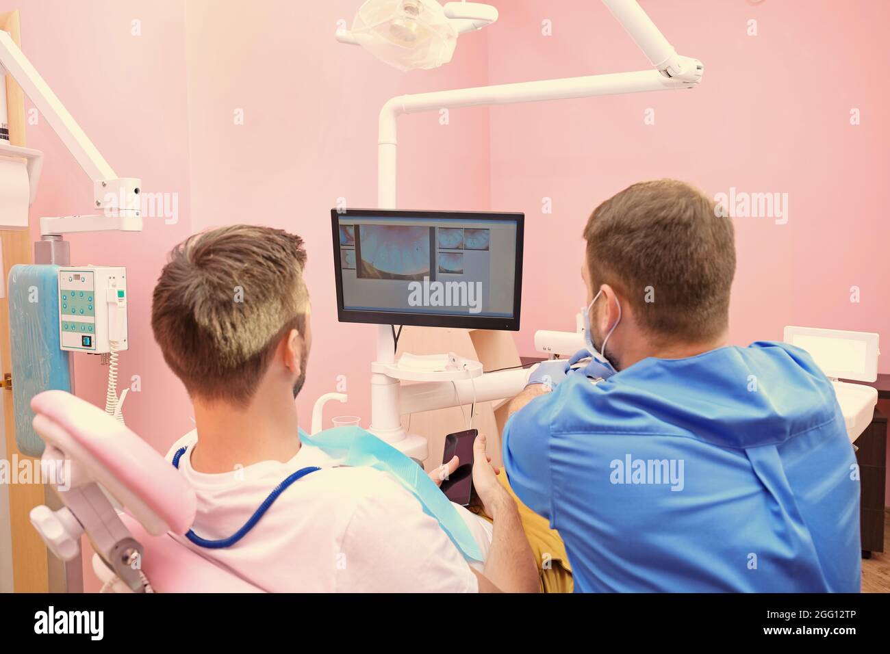 Dentist showing patient photos of teeth on monitor in clinic Stock