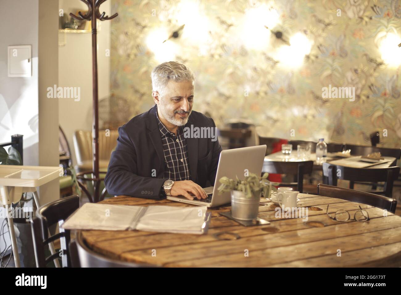 Elder Hungarian using a laptop inside a restaurant Stock Photo