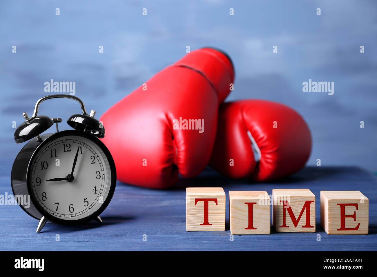 Cubes with alarm clock and boxing gloves on color background. Time
