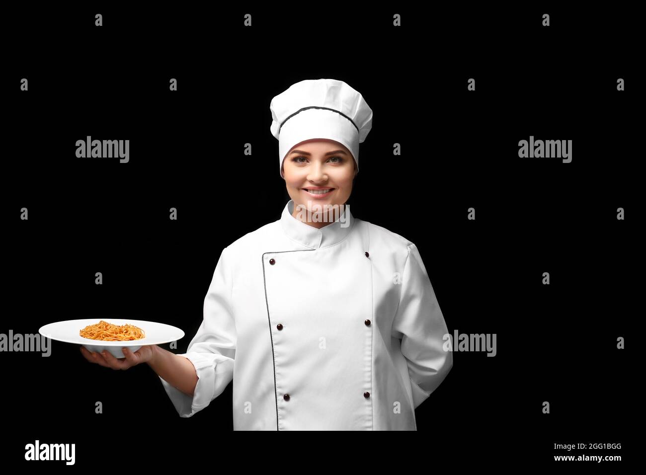 Portrait of young woman chef holding plate with pasta on black background  Stock Photo - Alamy