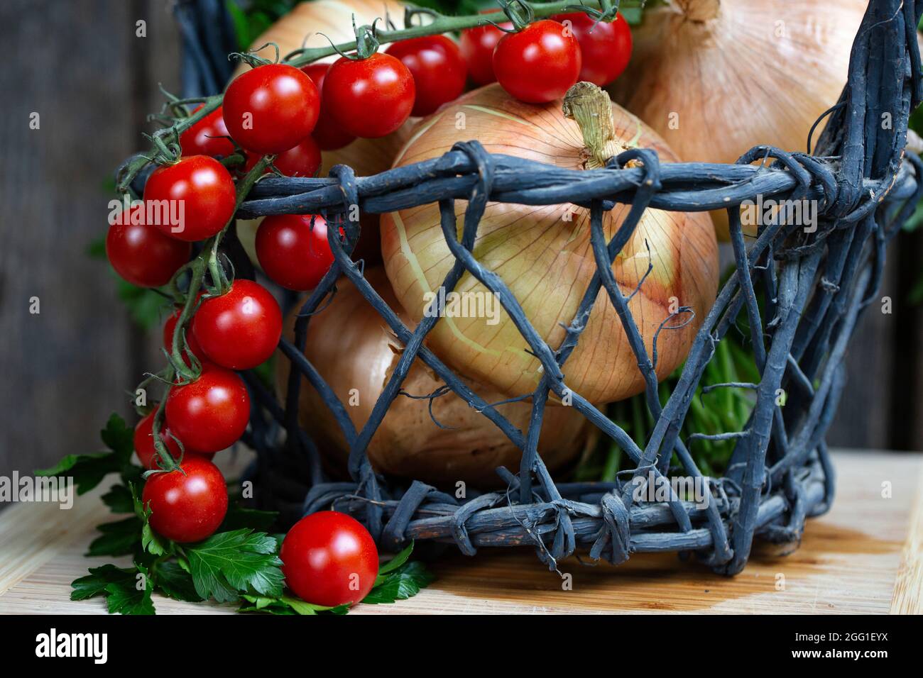 Cherry tomatoes, onions and parsley in a basket Stock Photo - Alamy