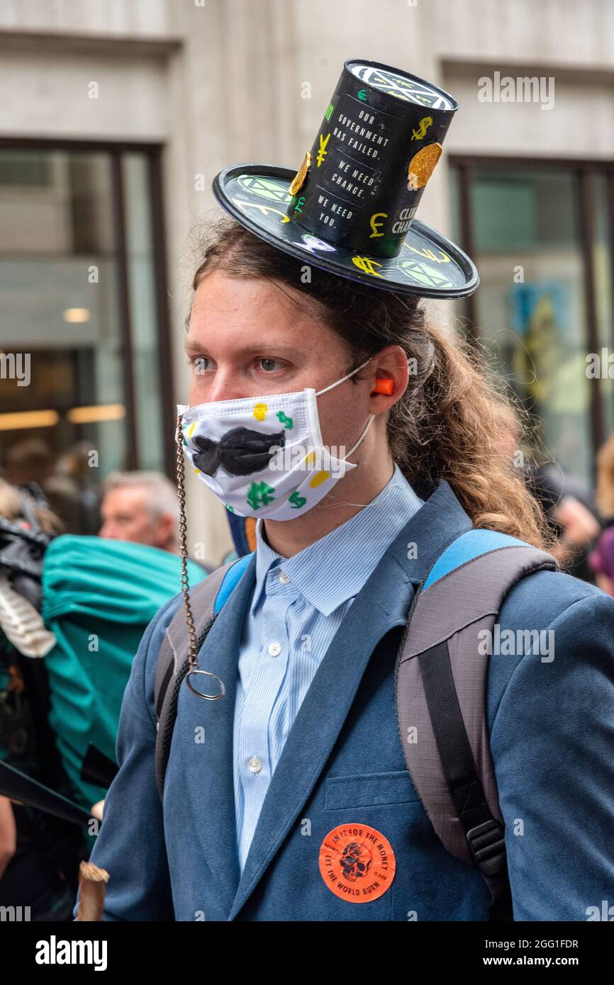 London, UK. 27th Aug, 2021. An Extinction Rebellion's Impossible Rebellion protester wears an unusual hat during the Blood Money march by Decolonise the Economy' claiming the City of London was built on Blood Money. Credit: SOPA Images Limited/Alamy Live News Stock Photo
