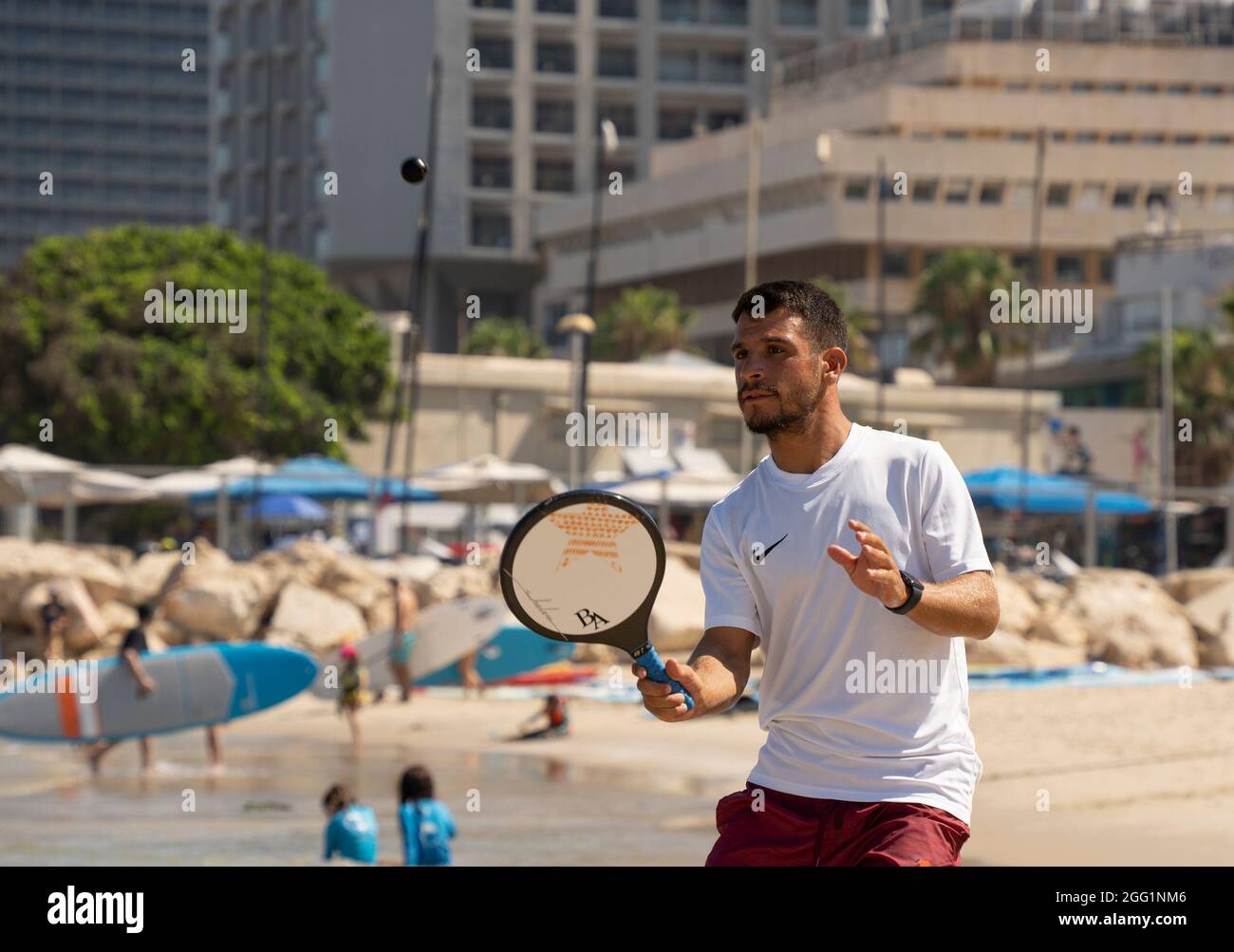 Tel Aviv, Israel - August 15th, 2021: A young man during a game of matkot on the Tel Aviv, Israel, beach, on a clear, sunny day. Stock Photo